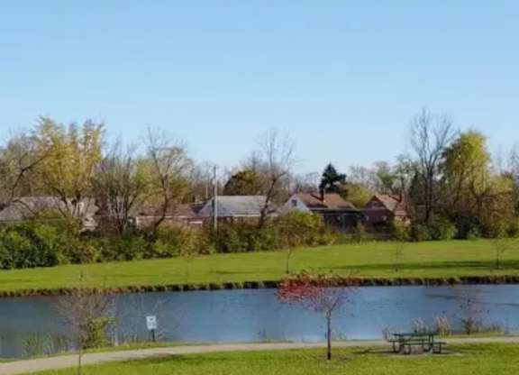 A serene park with a lake, trees, and a bench.
