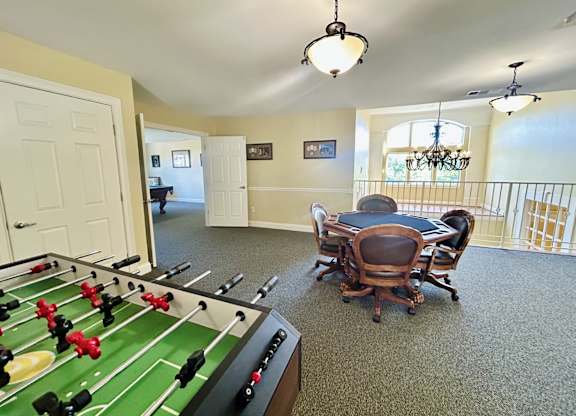 A foosball table is in the middle of a room with a dining table and chairs.