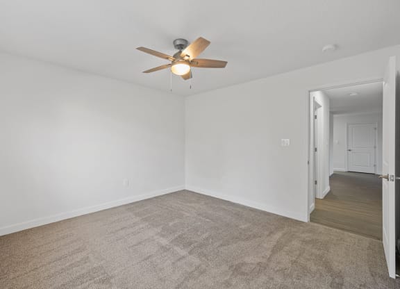an empty living room with white walls and a ceiling fan