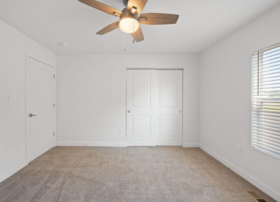 an empty living room with a ceiling fan and a door