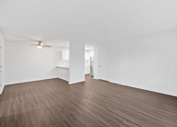 an empty living room with wood flooring and a ceiling fan