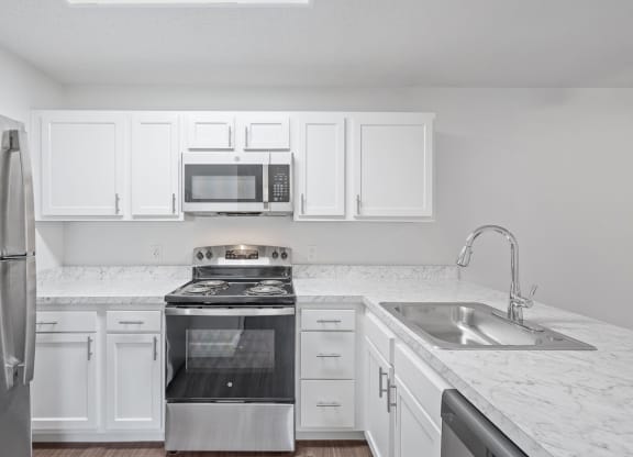 an empty kitchen with white cabinets and stainless steel appliances
