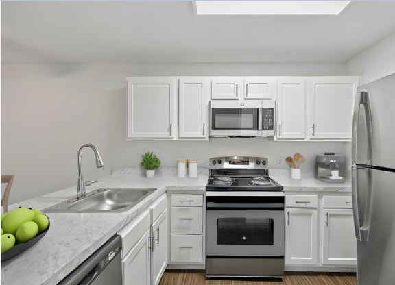 an apartment kitchen with stainless steel appliances and white cabinets