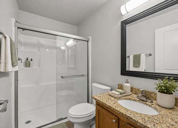 A bathroom with a toilet, sink, and shower.