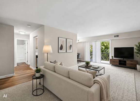 A living room with a white couch, a coffee table, and a television.