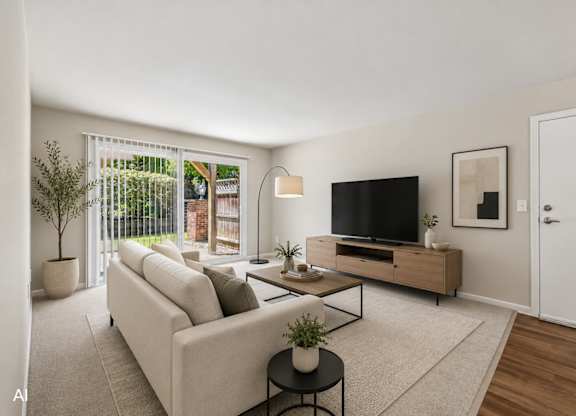 A living room with a white couch, a black TV, and a plant on a table.