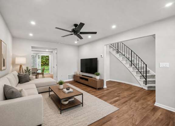 A living room with a couch, a coffee table, and a staircase.