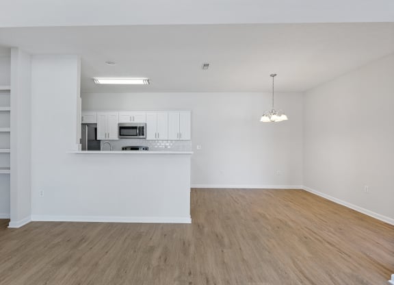 an empty living room and kitchen with white walls and wood flooring at Four Bridges, Liberty Township, OH, 45044-8380