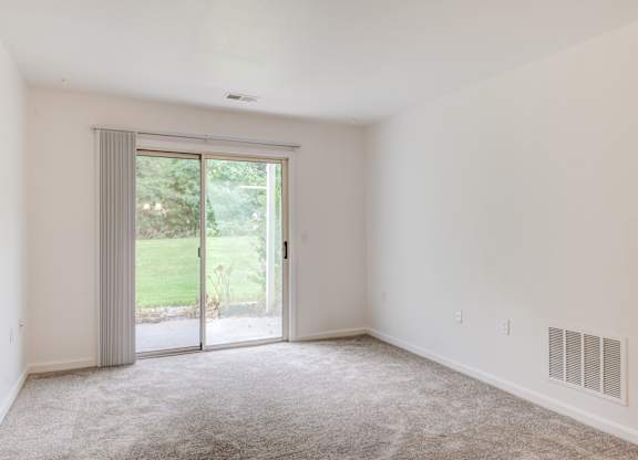 a living room with white walls and a sliding glass door