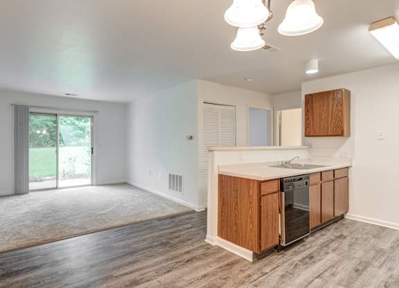 an empty kitchen and living room with a sliding glass door to a yard