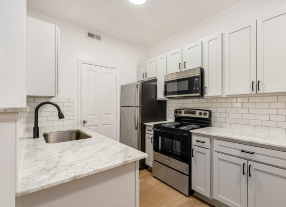 a kitchen with white cabinets and stainless steel appliances