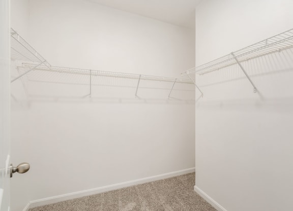 a walk in closet with white walls and shelves and a glass door