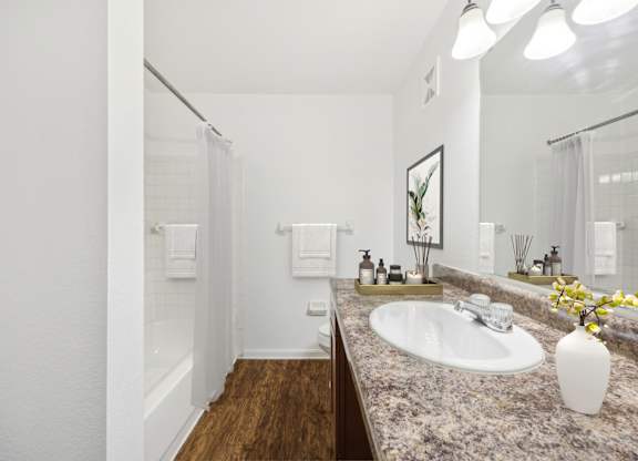 A bathroom with a sink, mirror, and a vase of flowers.