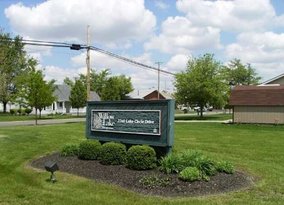 a green sign sitting in the middle of a grass field