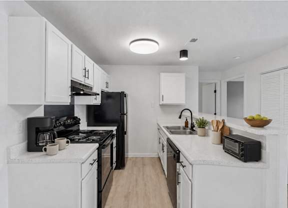 A modern kitchen with black appliances and white cabinets.