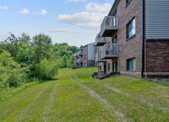 a grassy area with a brick building on the left and trees on the right at The Woodridge Collection, Fairfield