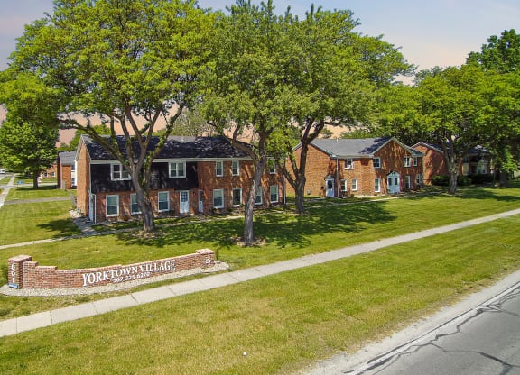 an aerial view of a brick house on the side of a street
