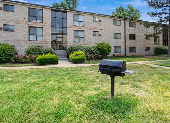 A black mailbox sits on a green lawn in front of a brick building at Rose Hill Apartments, Alexandria