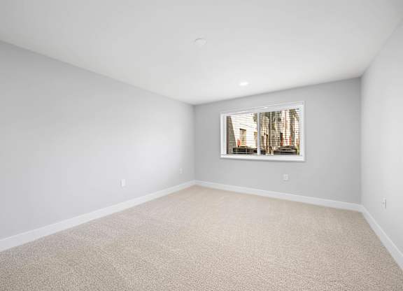 A room with a carpeted floor and a window showing a building outside at Rose Hill Apartments, Alexandria, VA