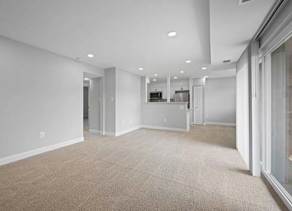A spacious, empty room with a carpeted floor and white walls at Rose Hill Apartments, Alexandria, VA