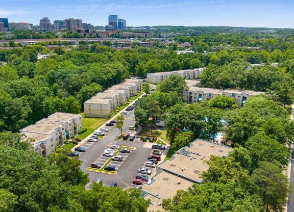 an aerial view of an apartment complex with trees and a city in the background