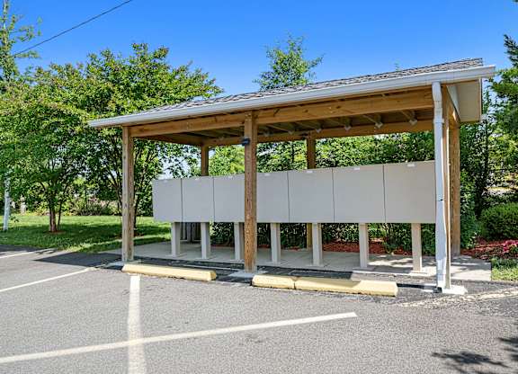 a bus stop with a roof and benches in a parking lot at Gainsborough Court Apartments, Fairfax, VA