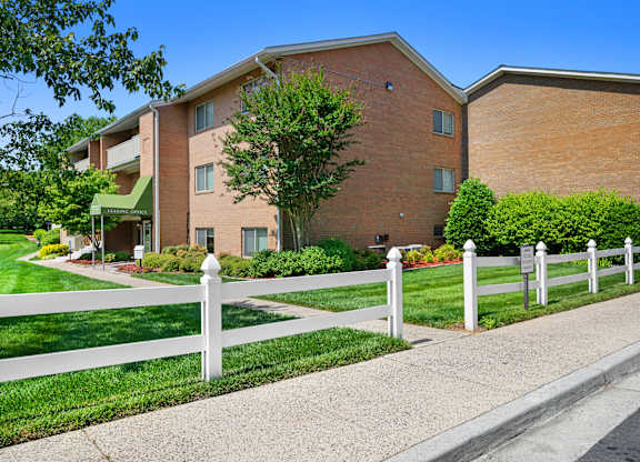 a white fence in front of a brick building at Gainsborough Court Apartments, Virginia