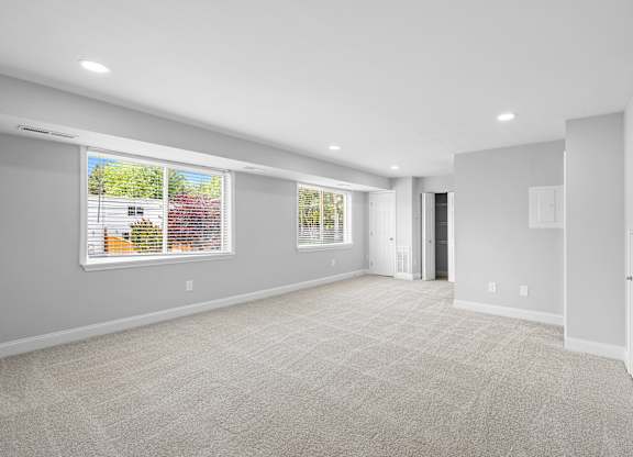 an empty living room with a large window and a door at Gainsborough Court Apartments, Fairfax, 22030