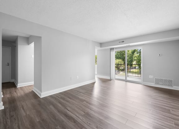 the living room of an empty apartment with wood flooring and a sliding glass door