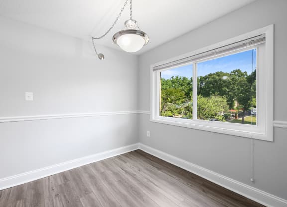 an empty bedroom with a large window and wood flooring