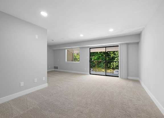 a living room with white walls and a door to a balcony at Gainsborough Court Apartments, Fairfax, 22030