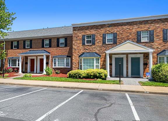 a red brick building with blue doors and a parking lot at Gainsborough Court Apartments, Virginia