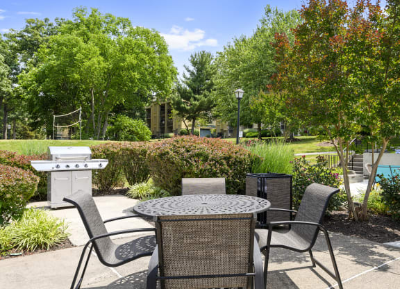 a patio with a table and chairs and a grill