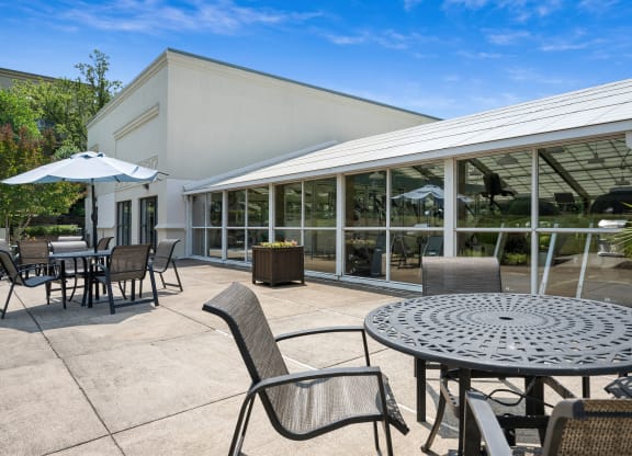 a patio with tables and chairs and a building in the background
