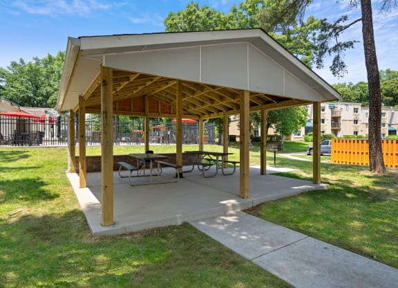 a picnic pavilion with benches and tables in a park