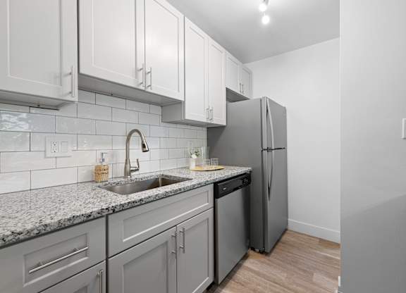 a kitchen with white cabinets and a sink and a refrigerator at Gainsborough Court Apartments, Virginia, 22030