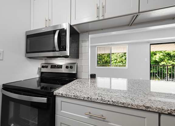 an updated kitchen with granite counter tops and black appliances at Gainsborough Court Apartments, Fairfax, VA