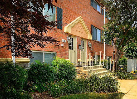A red brick building with a green bush in front at Gainsborough Court Apartments, Virginia, 22030
