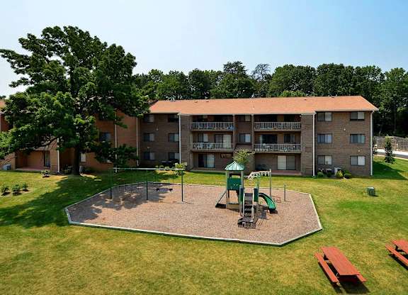A playground with a green slide and a red bench in front of a building at Gainsborough Court Apartments, Fairfax, Virginia