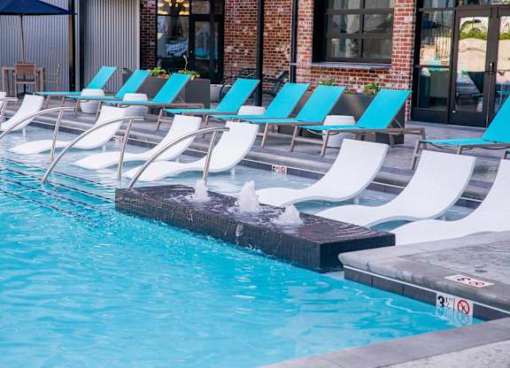 a swimming pool with white and blue chairs next to itat Sterling Nashville West Apartments, Nashville, TN