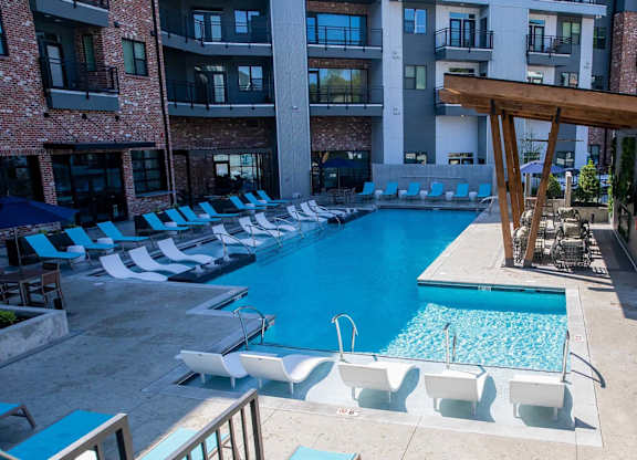 A large swimming pool with lounge chairs and a wooden pergola at Sterling Nashville West Apartments, Tennessee, 37209