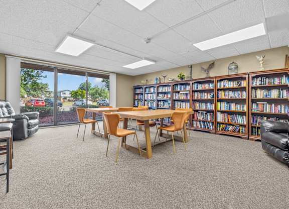 A room with a table, chairs, and a bookshelf filled with books.