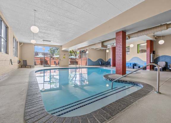 A large indoor swimming pool with a tiled edge and a metal ladder.