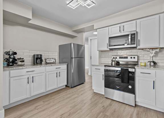 A modern kitchen with white cabinets and stainless steel appliances.