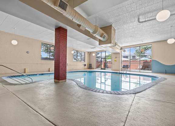 A large indoor swimming pool with a red pillar and a metal ladder.