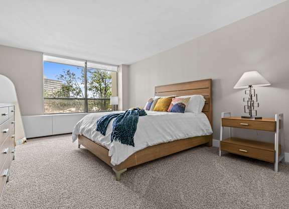A bedroom with a large bed and a window overlooking a cityscape.