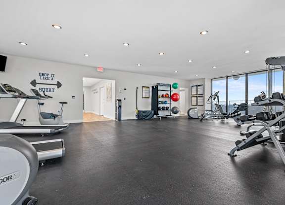 A gym with a variety of equipment including treadmills, weights, and a squat rack.