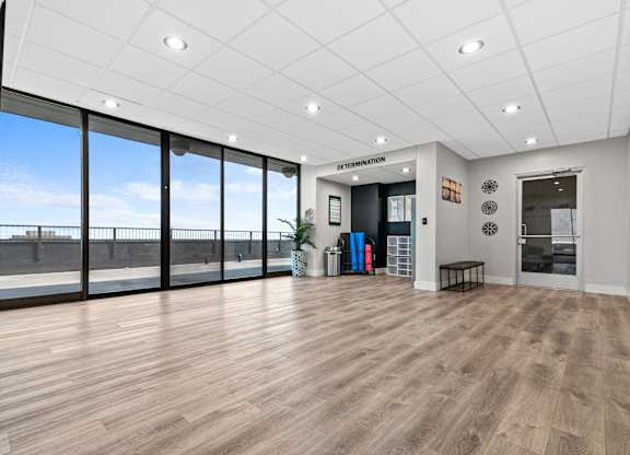 A spacious room with wooden flooring and a large window overlooking a bridge.