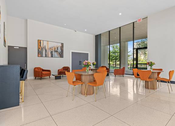 A room with orange chairs and a dining table.