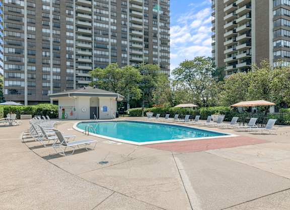 A swimming pool surrounded by lounge chairs in a residential area.